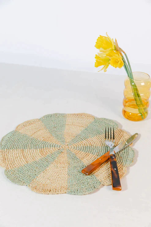 Blue pinwheel-shaped placemat made of raffia, designed for tabletops by Payton James, showcasing a textured, decorative table setting.