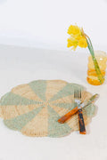 Blue pinwheel-shaped placemat made of raffia, designed for tabletops by Payton James, showcasing a textured, decorative table setting.