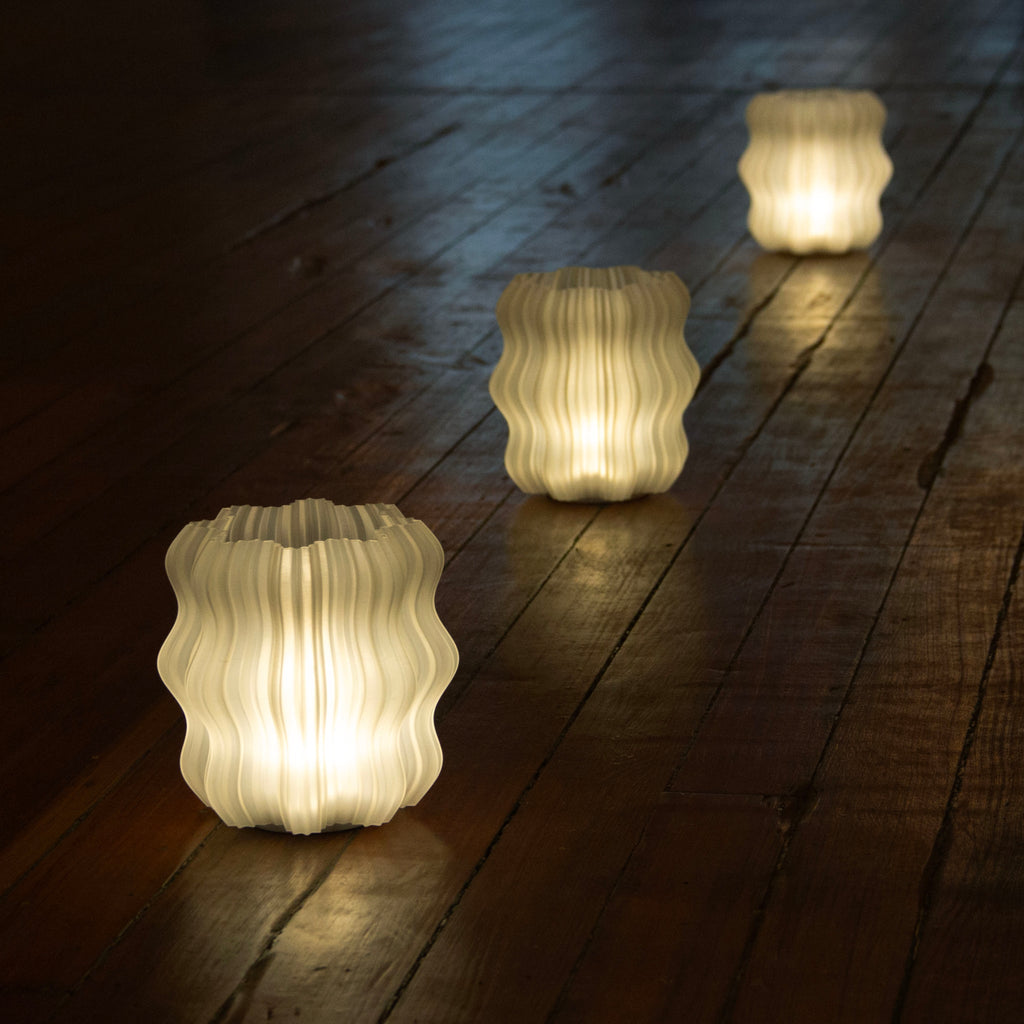 Wooj Design cordless mini wavy lamp on a desk, showcasing its sleek, modern design with soft lighting in a cozy workspace setting.
