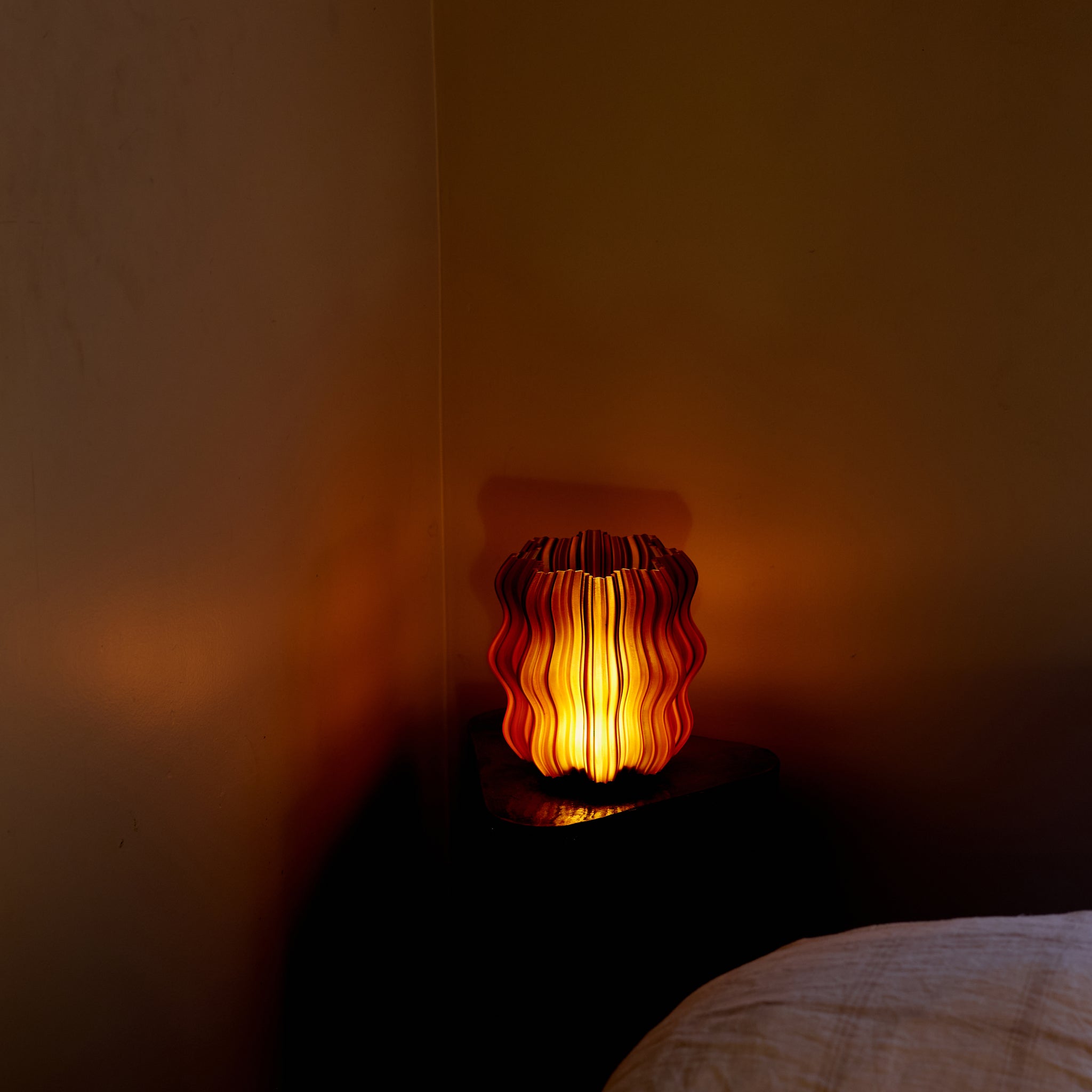Close-up of Wooj Design cordless mini wavy lamp in amber, highlighting its textured, wavy surface and compact design.