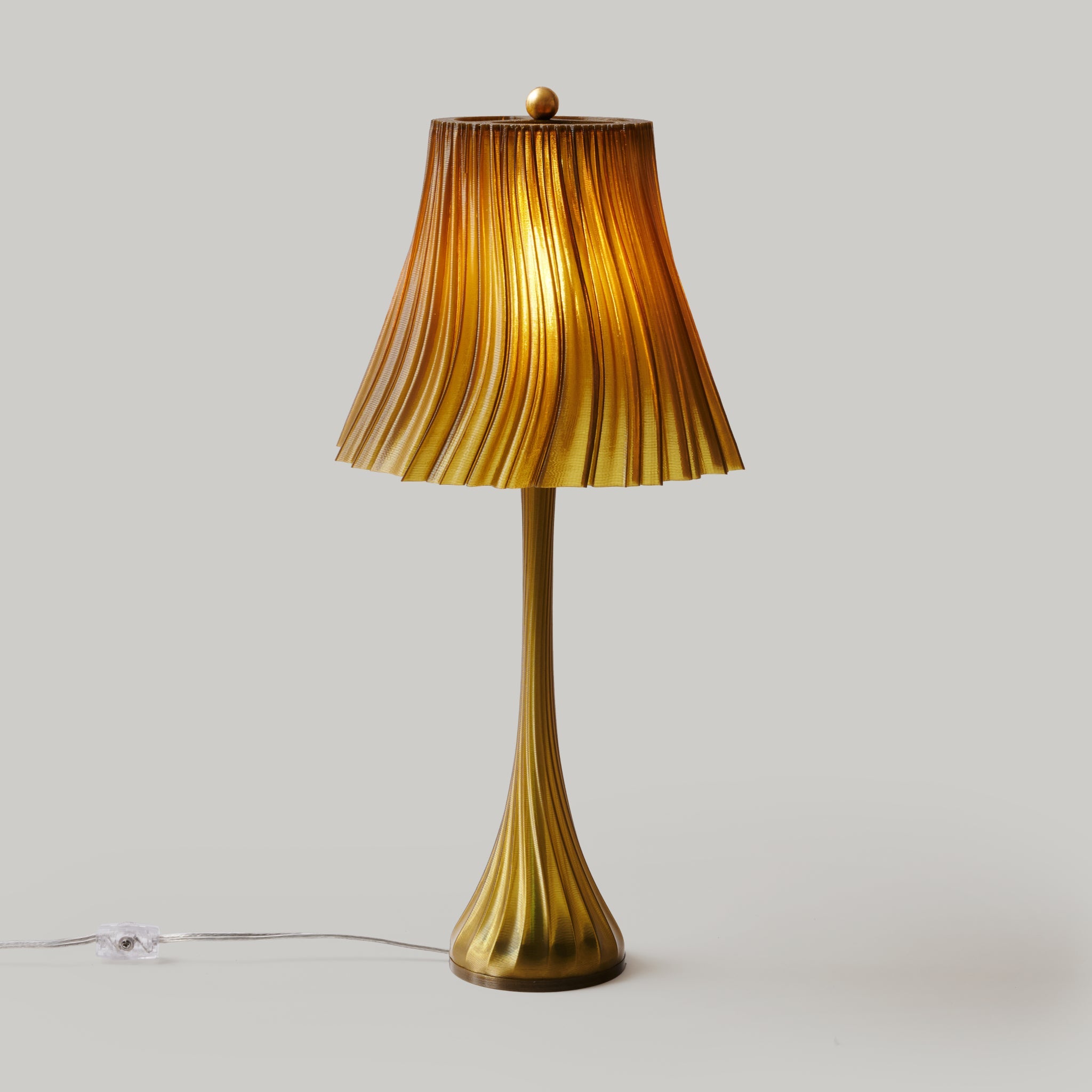 Wooj Design pleat lamp with a soft green fabric shade and sleek modern design, shown in a well-lit interior setting.