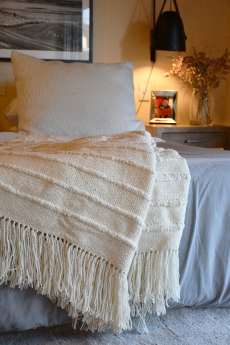 Homelosophy multi-striped natural throw blanket draped over a sofa, showcasing its cozy, soft fabric and colorful striped pattern.