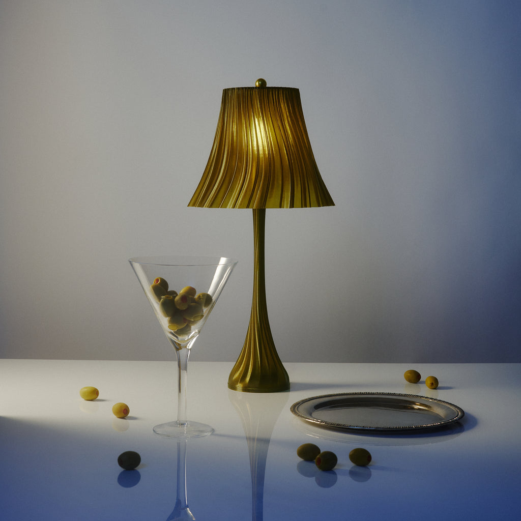 Wooj Design Pleat Lamp with a sleek, folded fabric shade in a cozy olive oil color, styled in a modern living space.