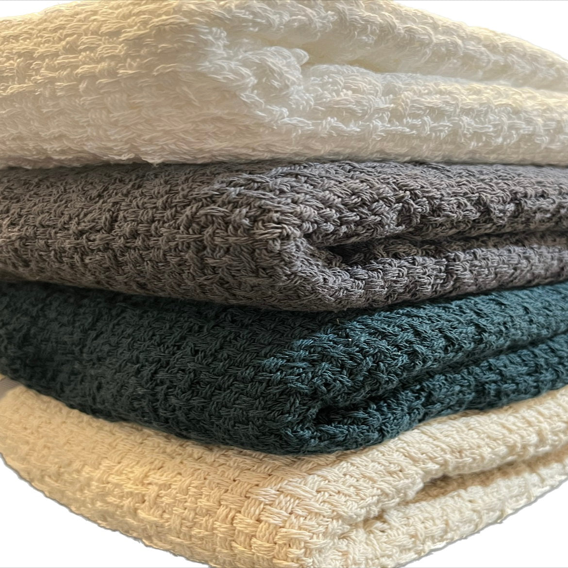 Stack of Carolina Cottons 100% cotton throw blankets measuring 52 by 65 inches, soft and cozy with woven textures.
