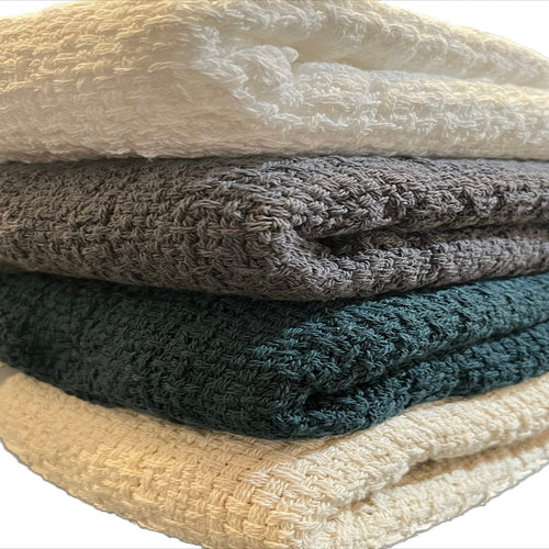 Stack of Carolina Cottons 100% cotton throw blankets measuring 52 by 65 inches, soft and cozy with woven textures.