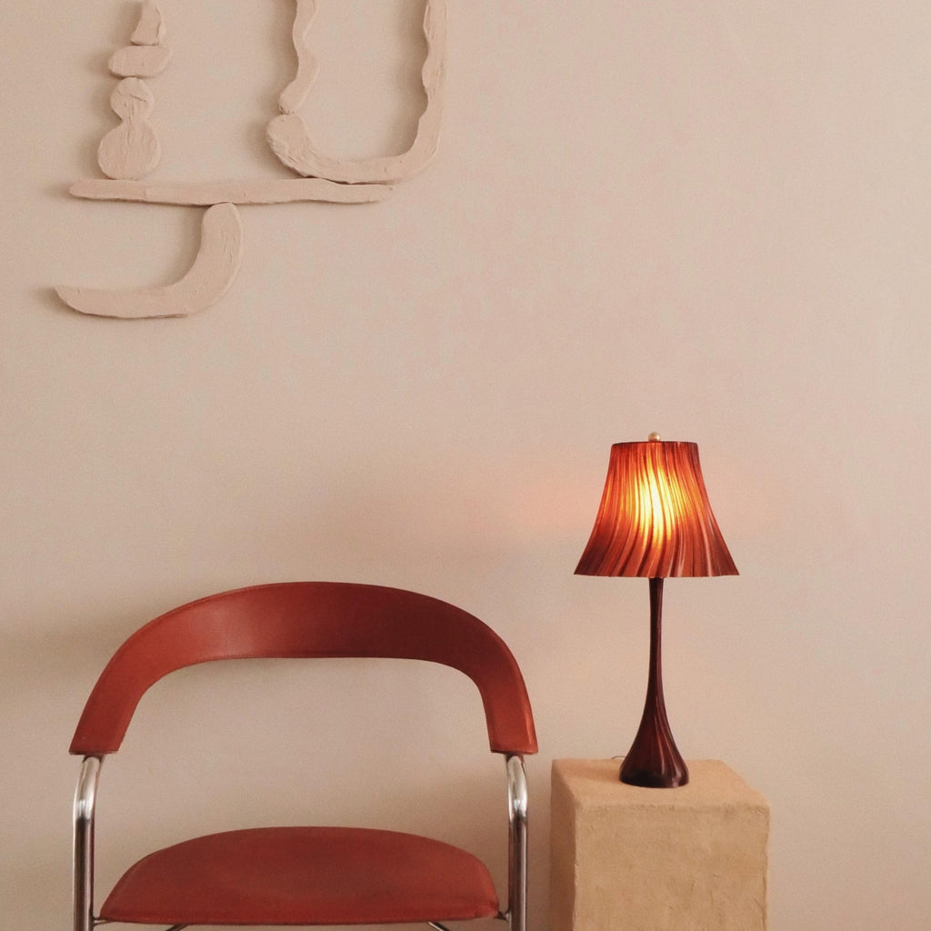 Wooj Design Pleat Lamp with pleated fabric shade and modern design, illuminated against a neutral background.