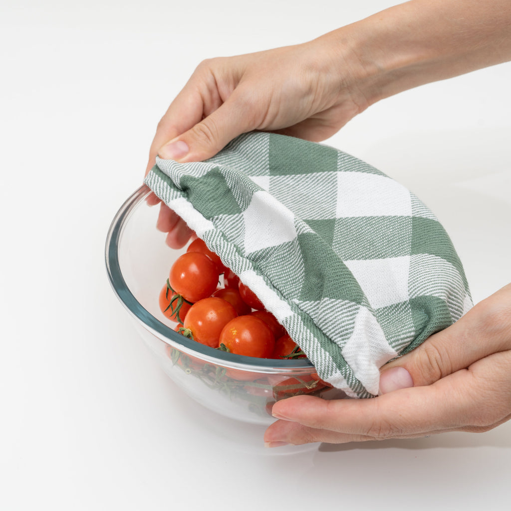Sage green cloth bowl covers made of organic cotton with elastic edges for a secure fit on bowls.