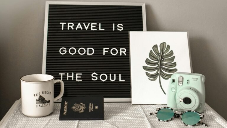 A travel-themed flat lay with a camera, coffee, and motivational quote.