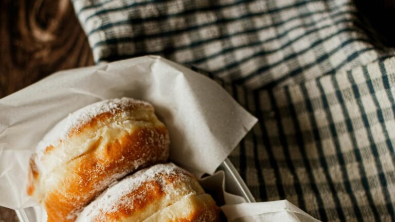 Three donuts with powdered sugar paired with a cup of black coffee, captured in warm natural light.