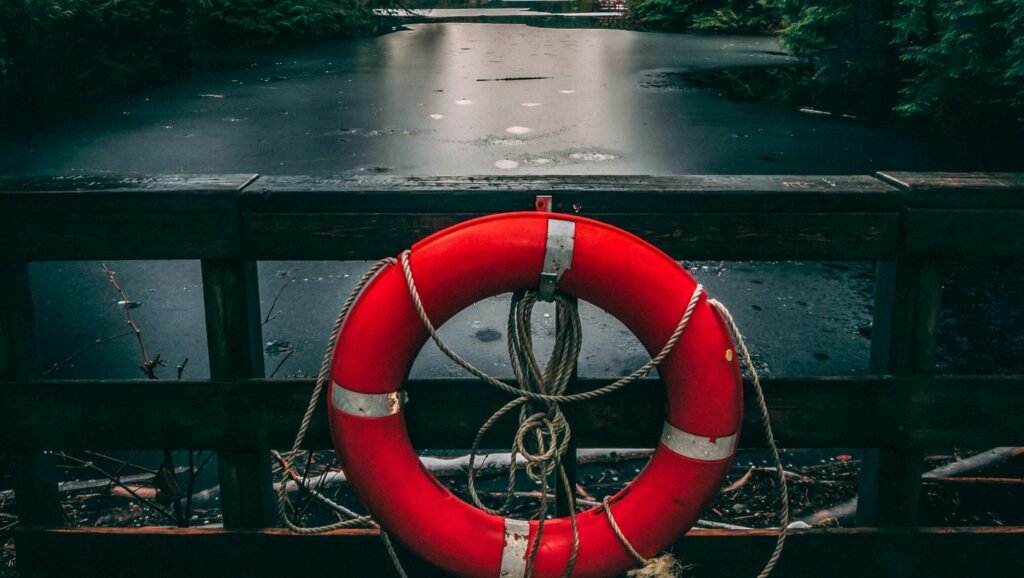 Red life buoy hanging on a railing overlooking a serene lake surrounded by dense forest in North Vancouver.