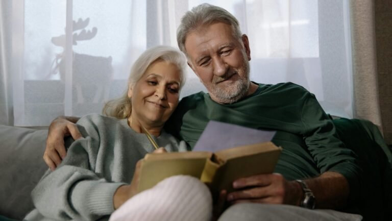 An elderly couple sharing a joyful moment while reading together at home.