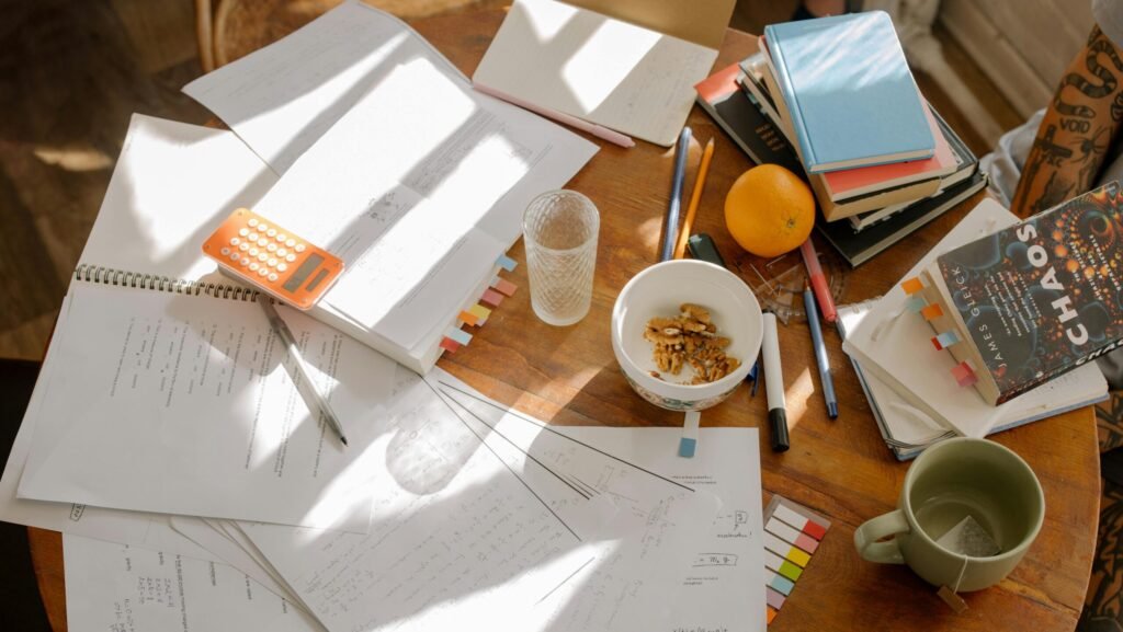 A cluttered study table with books, notes, and study materials in natural light for focused exam preparation.