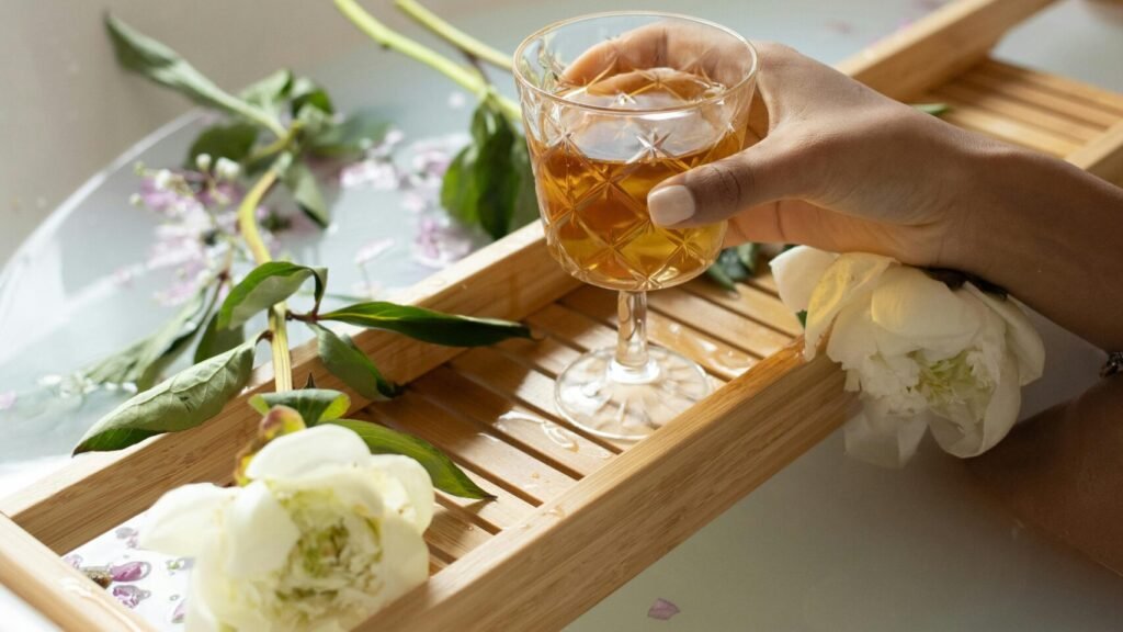 Serene bathtub scene with flowers, aromatherapy, and a drink.
