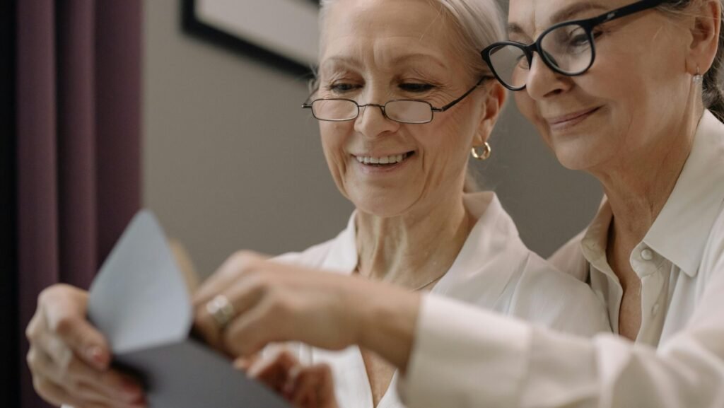Senior women couple joyfully reading a letter together in their home.